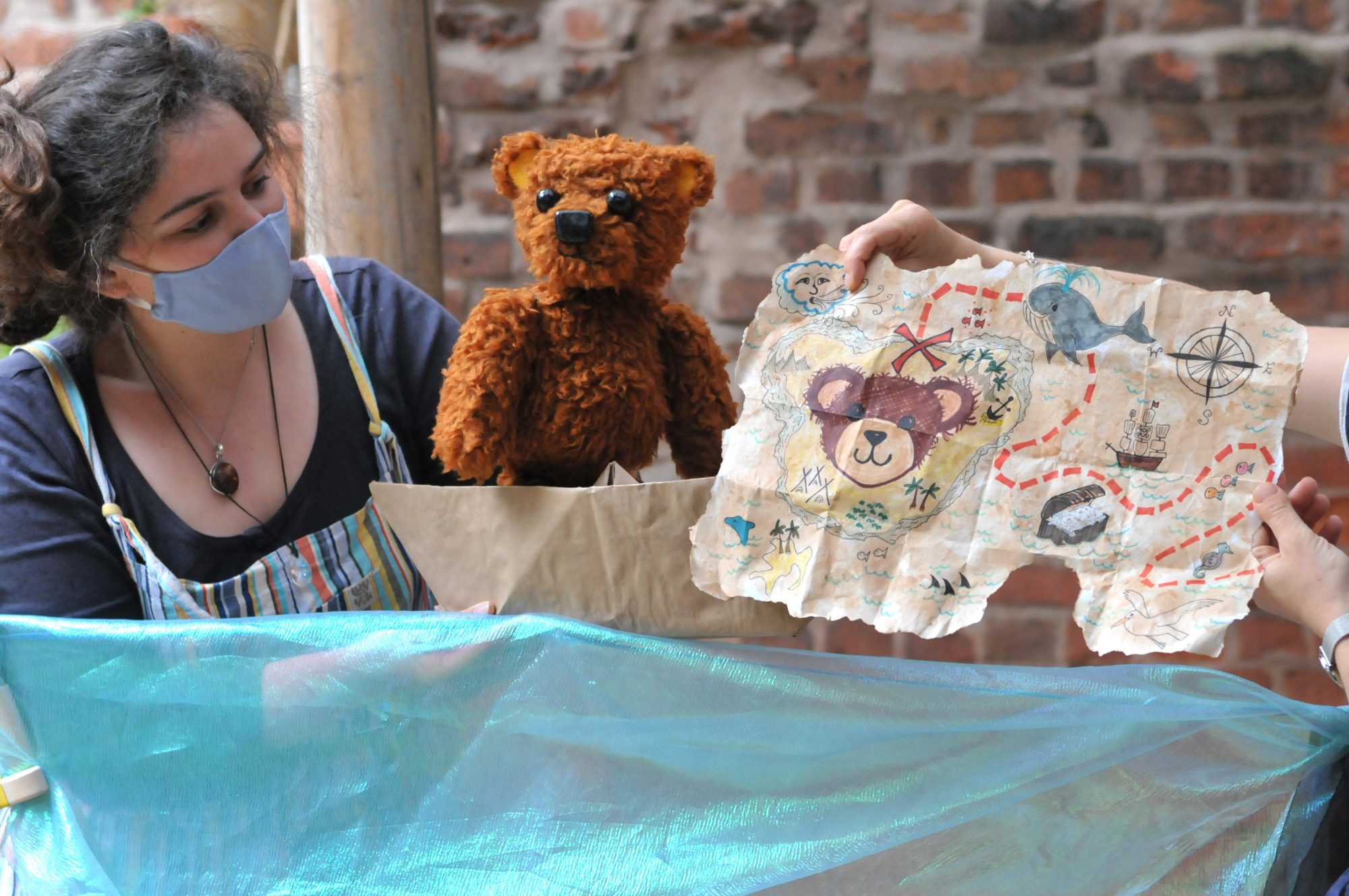 GPT A woman wearing a mask shows a hand-drawn treasure map to a teddy bear.