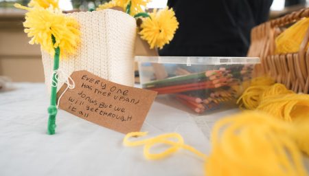 Yellow yarn flowers and a handwritten tag reading 