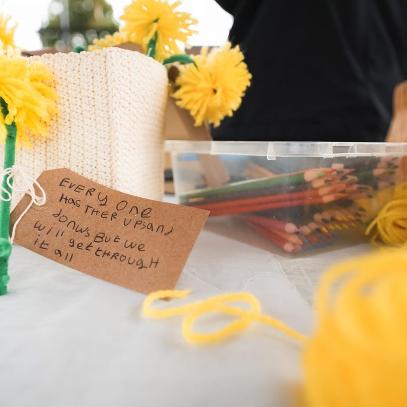 Yellow yarn flowers and a handwritten tag reading 