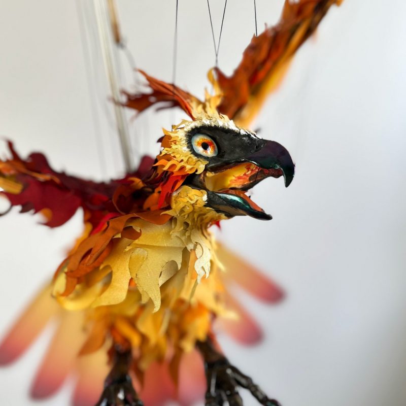 GPT An intricately crafted marionette of a phoenix with a vivid array of fiery feathers in mid-flight, suspended by strings.
